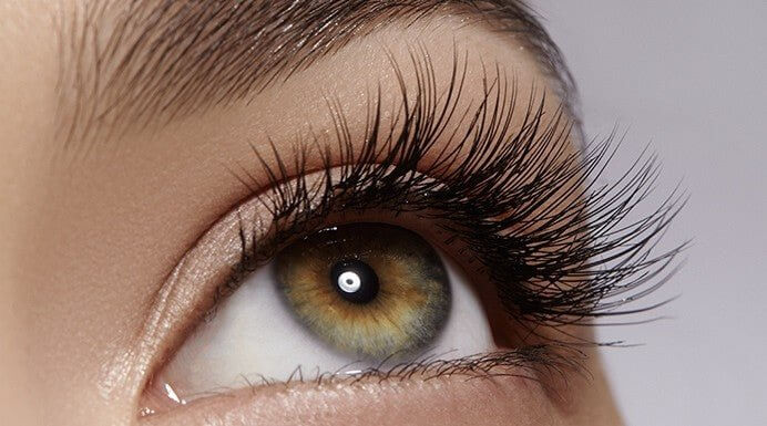 Close-up of eye looking upward showing extremely long, thick lashes after using MD Lash Factor 6-month serum